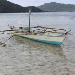 A lone boat in the clear waters around Snake Island in El Nido by facemadeup.com